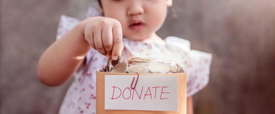Children with Donation Concept. 2 Years Old Child putting Money Coin into a Donate Box